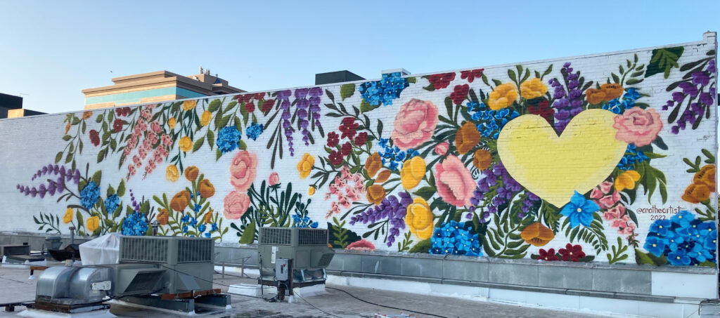 Ana Honsowetz’s “The Heart of Vancouver.” A bright yellow cartoony heart amidst flowers, all on a white background.