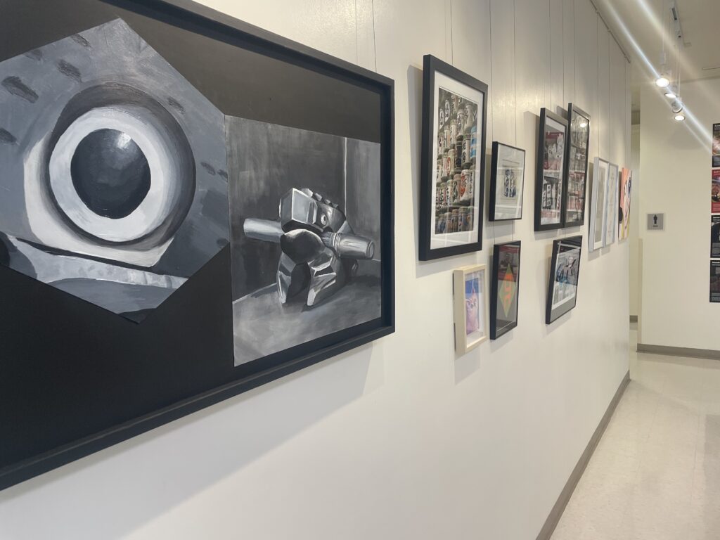 A photo showing one wall of the VDEN art gallery, including artworks showcasing a Noir eyeball looking figure. Photo taken by Jonah Barnett.